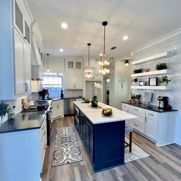 a modern kitchen with an island, hanging ceiling lights, vinyl flooring
